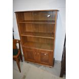 A vintage mid stain bookcase by Ercol, having glazed upper section with two adjustable shelves and