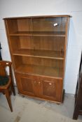 A vintage mid stain bookcase by Ercol, having glazed upper section with two adjustable shelves and