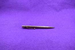 A Propelling pencil in 9ct gold with engine turned decoration, stamped 9 .375 to tip, barrel and