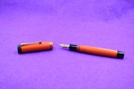 A Parker Duofold Lucky Curve Jr button fill fountain pen in orange with a single band to cap and