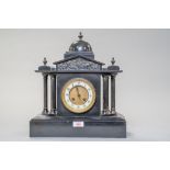 An antique chiming mantle clock of black polished stone having painted metal columns to sides,