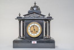 An antique chiming mantle clock of black polished stone having painted metal columns to sides,