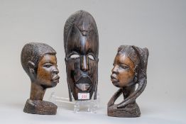 A pair of African tribal heads carved in heavy ethnic woods and a carved wall mounted mask.