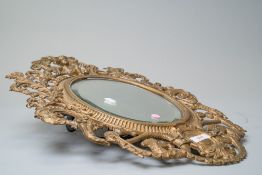A Victorian hall way mirror of oval form with an elaborately cast iron frame with peacock and cherub