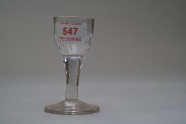 A small spirit glass having fluted decoration to the bowl and a plain stem.