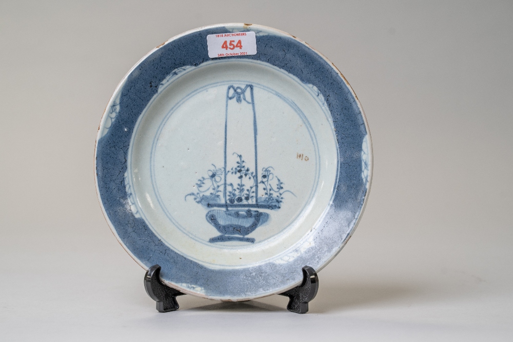 A Chinese or Japanese export plate in hard paste ceramic hand painted with flower basket scene and a