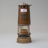 An antique coal miners or similar safety lamp having a copper and brass casing bearing name badge
