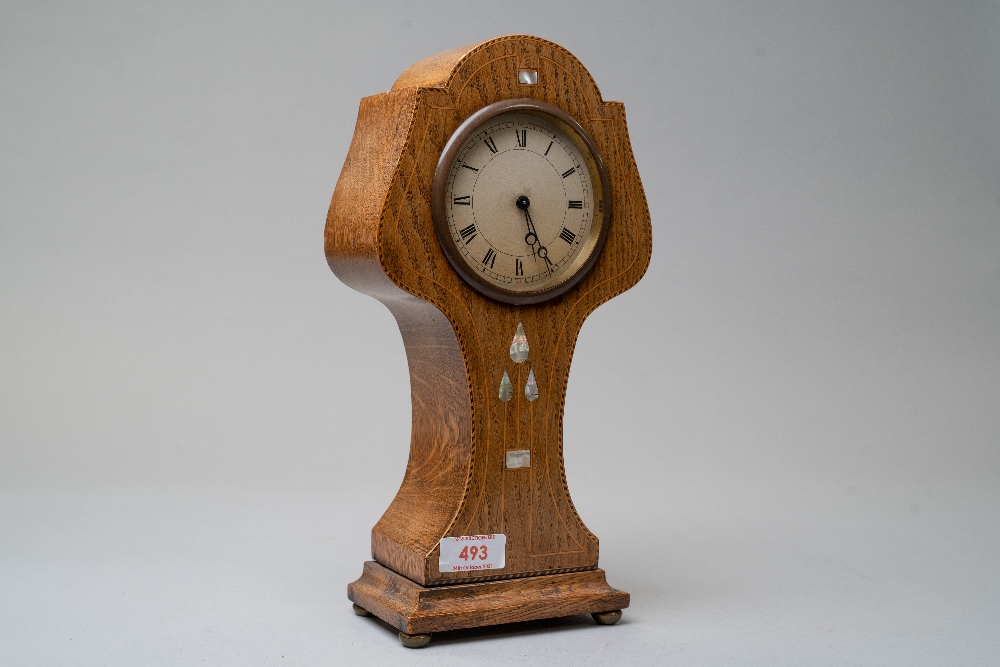 An Edwardian Swiss made tulip or almost balloon shaped oak mantel clock having satinwood and similar