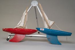 Two vintage wooden sailing yachts, one red and the other blue 'Star yacht, guaranteed to sail,