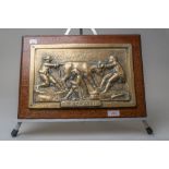 A metal plaque having raised scene depicting three men and a bull titled 'The law suit' mounted on