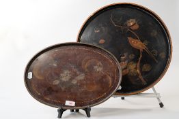 A late 19th/early 20th century round black lacquered tray having painted bird and flower design