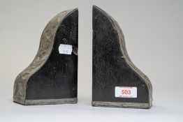 A pair of ebonised bookends in the arts and crafts style having raised metal work cladding to