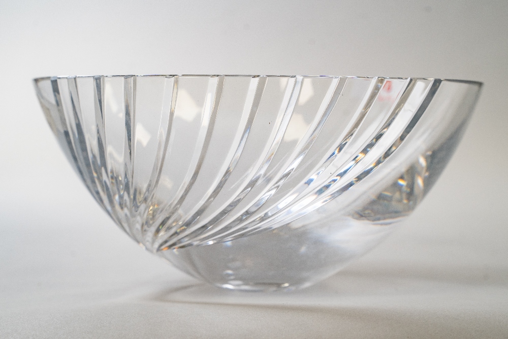 A modernist style clear cut crystal glass fruit bowl having a wave form expanding cut to one side