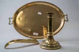 A vintage oval brass tray having handles to sides, a brass shoe horn and a brass candle stick