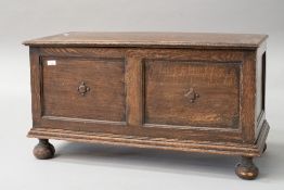 An early 20th Century oak panelled kist/bedding box having applique decoration, on bun feet,