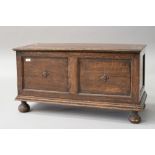 An early 20th Century oak panelled kist/bedding box having applique decoration, on bun feet,