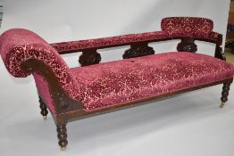 A Victorian chaise longue having carved frame including back rail, turned legs and brass castors,