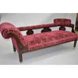 A Victorian chaise longue having carved frame including back rail, turned legs and brass castors,