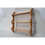 A natural pine triple wall shelf of small proportions with plate grooves to each and shaped ends,