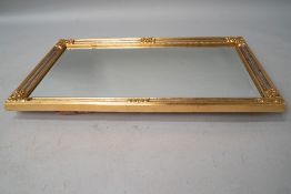 A modern reproduction gilt frame wall mirror in the classical style with foliate embellishments, and