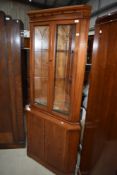 A reproduction yew wood corner display cabinet with cupboard under, from the William Bartlett