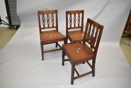 A set of three period oak dining chairs having shaped slat and rail backs, solid seats and square.