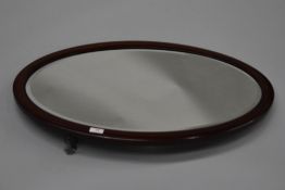 An early 20th Century mahogany framed oval wall mirror, hung in portrait orientation, approx 75 x