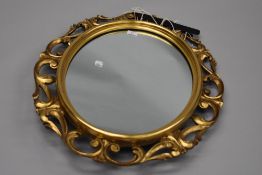 A traditional gilt frame wall mirror having oval centre surmounted with foliate scroll work, overall