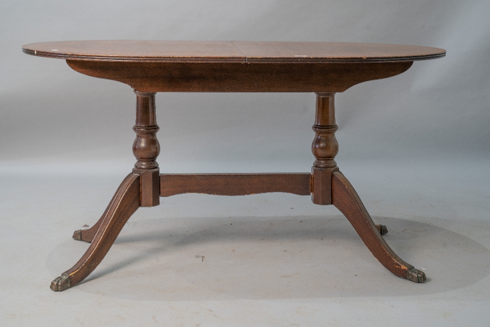 A reproduction Regency mahogany dining table of typical form with splay legs and brass paw feet,