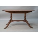 A reproduction Regency mahogany dining table of typical form with splay legs and brass paw feet,