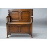 An early to mid 20th Century oak monks bench having plain top, panelled back and box section, bobbin