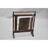 An early 20th Century firescreen having turned oak frame and tooled leather panel and strap work