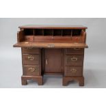 A hardwood kneehole desk in the 19th Century style having pull out desk to frieze, brass drop