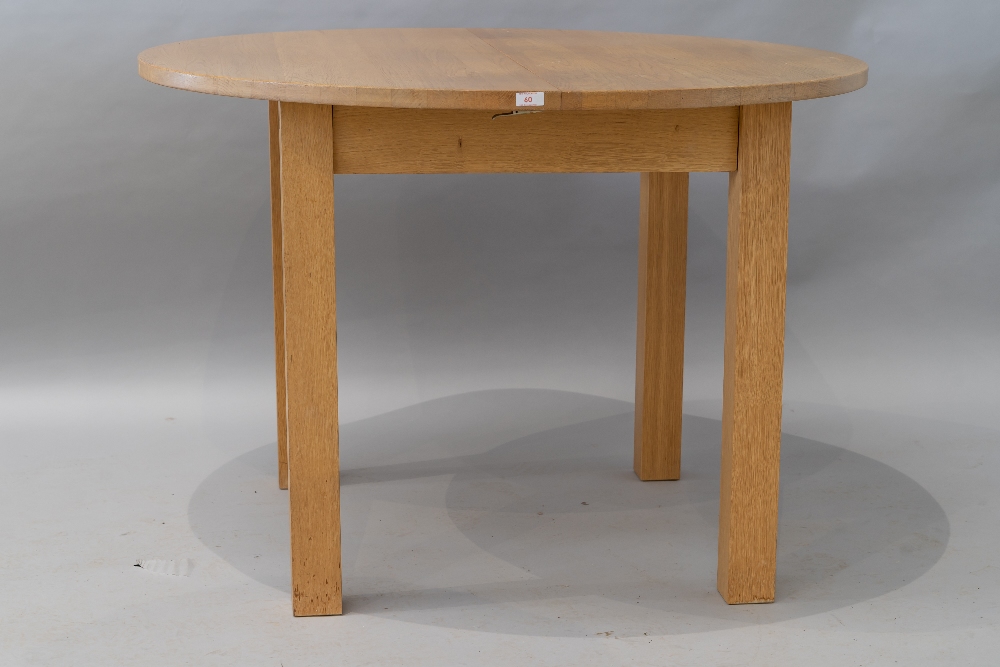 A modern circular golden oak dining table , having integral leaf extension on square chunky legs,