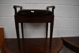 An early 20th Century mahogany frame piano stool of plain form with arm rests and square tapered