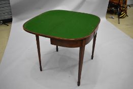 A late 19th or early 20th Century mahogany fold over games table with inlay decoration to frieze, on