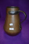 An antique copper water jug having a heavy body with bronze handle 27cm tall