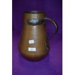 An antique copper water jug having a heavy body with bronze handle 27cm tall