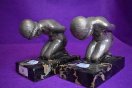 A pair of art deco design book ends or figure sculptures on kneeling maidens metal cast on black