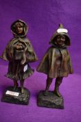 A pair of antique French spelter mantle figures of a boy and girl in cloaks