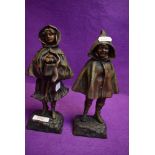 A pair of antique French spelter mantle figures of a boy and girl in cloaks