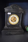 An antique mantle or bracket clock in a Gothic style having solid stone case with brass and enamel