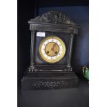 An antique mantle or bracket clock in a Gothic style having solid stone case with brass and enamel