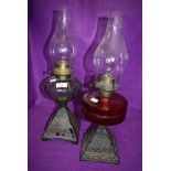 Two Victorian oil burning lamps having decorative cast bases with red and green oil wells