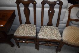 A pair of Period oak vase back dining chairs having later upholstery
