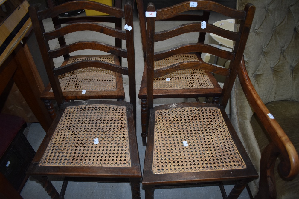 A pair of early 20th Century oak wave back bedroom chairs having cane work seats and twist leg