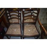 A pair of early 20th Century oak wave back bedroom chairs having cane work seats and twist leg