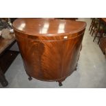 An early 20th Century mahogany demi lune side cabinet having flame mahogany doors, short cabriole