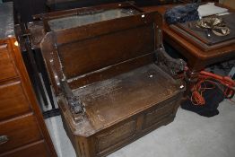 An early to mid 20th Century oak monks bench having lion arms, needs a freshen up