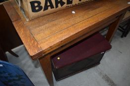 An early to mid 20th Century mid stain oak drawer leaf table with fold over top